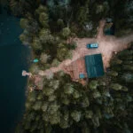 Aerial drone view of a wooden cabin by a lake at Bearhill husky in Lapland